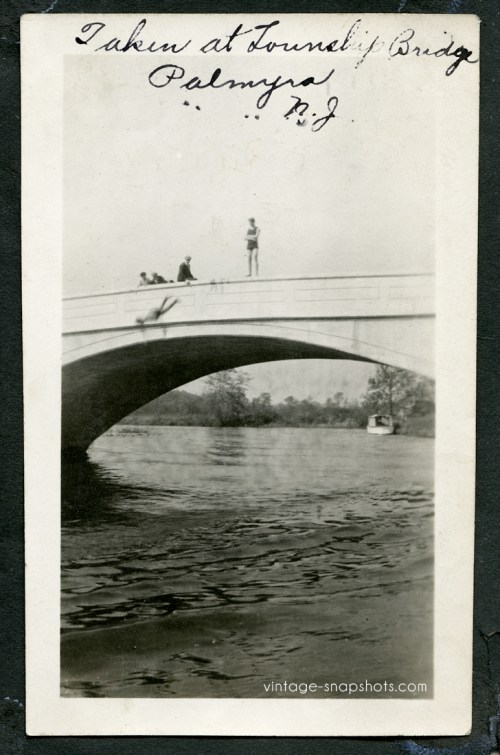 Vintage photo of person leaping from New Jersey bridge, circa 1910s, while their friends look on