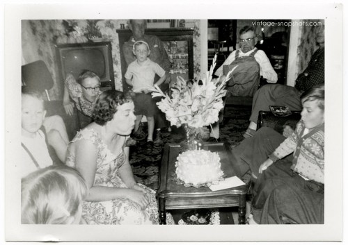 1950s family at birthday party, kids blowing out candles on cake