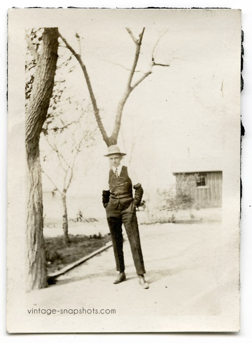 Vintage photo of a man standing in front of a tree, with the branches appearing to rise from his hat