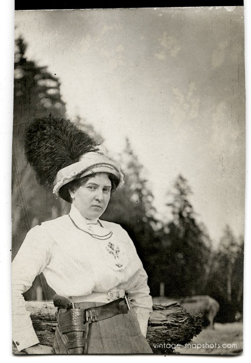 Vintage snapshot of woman with an amazing hat along with a pistol and extra bullets (circa 1900/1905)