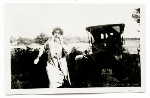 Circa 1920s snapshot of woman running, with parked car in background