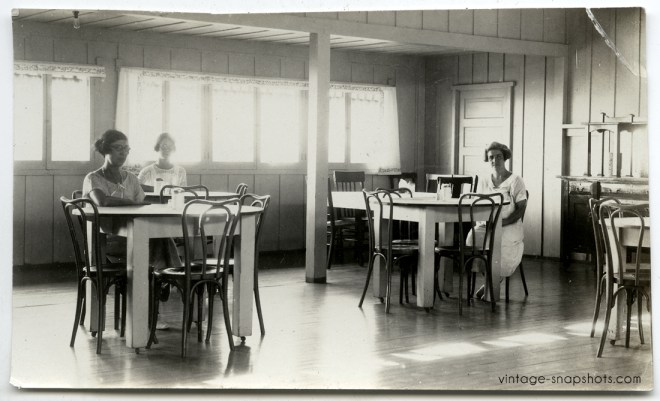 Circa 1920s vintage photo of women sitting alone at dining tables