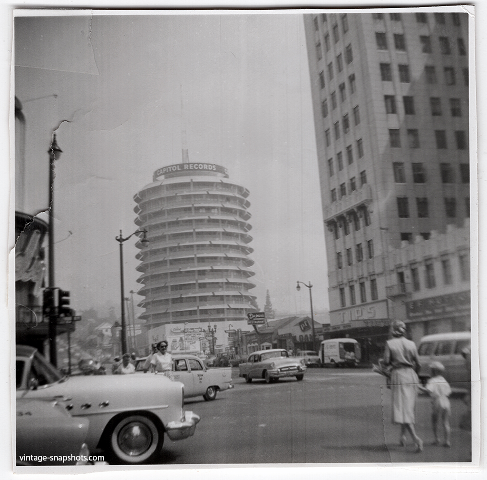 1960s snapshot of the intersection of Hollywood Blvd and Vine St, with pedestrians, traffic, shops and the Capitol Records tower